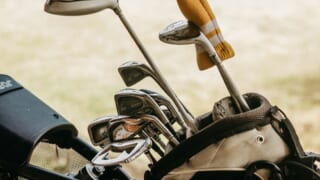 ゴルフ場に置かれたゴルフバッグとクラブ。コンペ参加費やプレー代の確認をイメージした写真